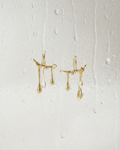 Gold earrings on a textured white background