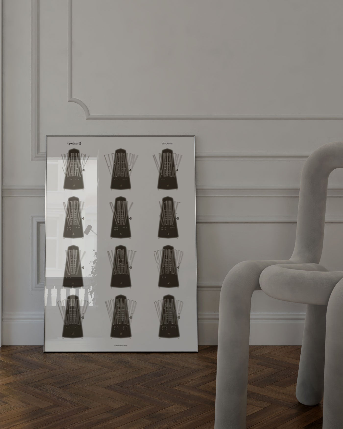 Brown and white 2026 wall calendar inspired by metronome, art print framed, on floor