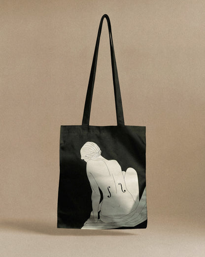 Black tote bag with a white silhouette design on a beige background