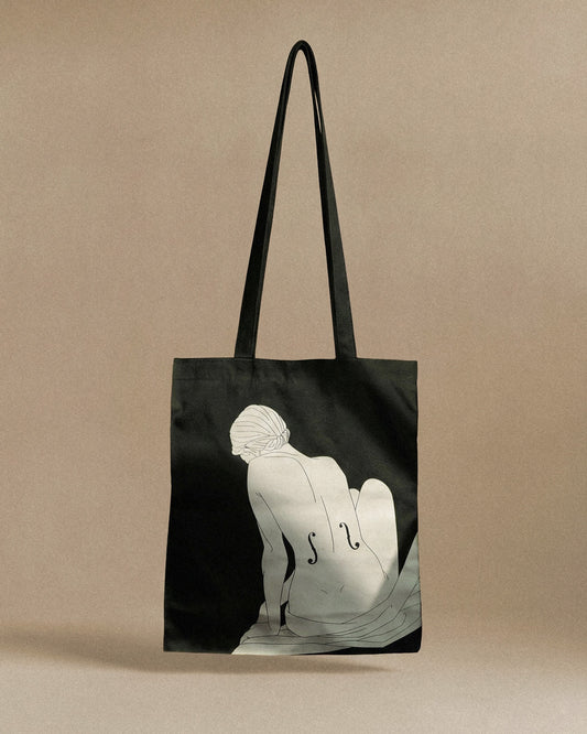 Black tote bag with a white silhouette design on a beige background