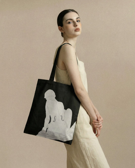 Woman holding a tote bag with an illustration silhouette design on a beige background