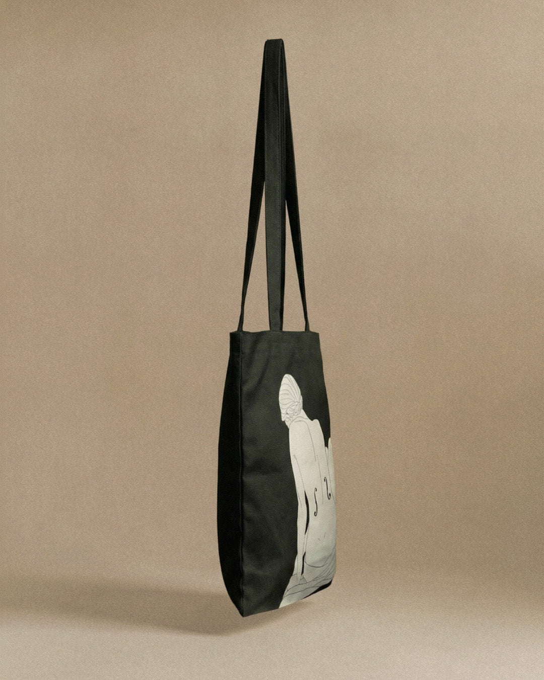 Black tote bag with a white silhouette design on a beige background