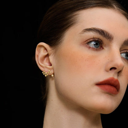 Close-up of a person wearing gold earrings with a black background