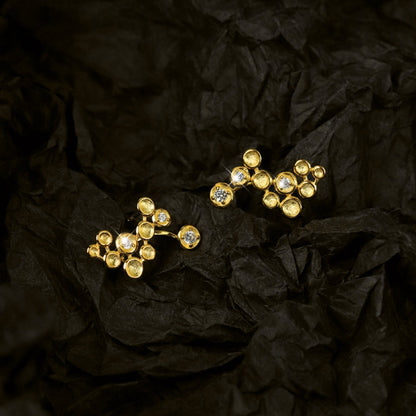 Gold earrings with gemstones on a black crumpled paper background